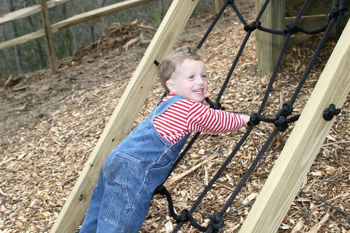 A child climbing a rope ladder structure outdoors.