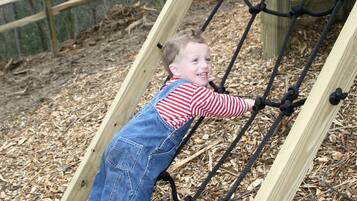 A child climbing a rope ladder structure outdoors.