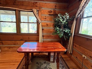 L'intérieur d'un chalet en bois, avec une table, des fenêtres et une plante.