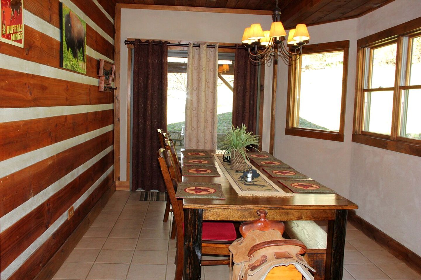 Un comedor con mesa de madera, sillas y una araña.