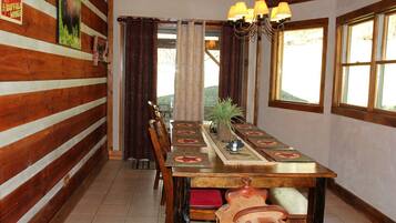 Un comedor con mesa de madera, sillas y una araña.