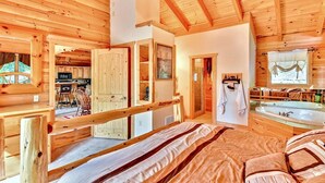 A wooden cabin interior with a bedroom, bathroom, and kitchen.