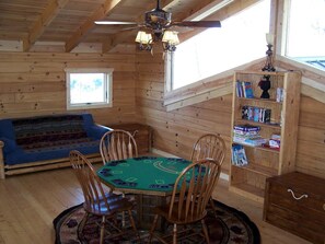 A wooden interior with a round table, chairs, a bookshelf, and a window. - Luxury Vacation Rental with a Hot Tub for Rent in Clyde, North Carolina (Clyde)