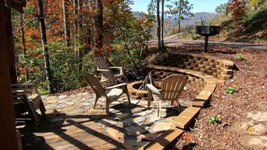 A patio area with Adirondack chairs, a fire pit, and a stone fire ring.