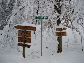 A directional signpost with multiple wooden signs pointing to various lodges and a castle. - Luxury Vacation Rental with a Hot Tub for Rent in Clyde, North Carolina (Clyde)
