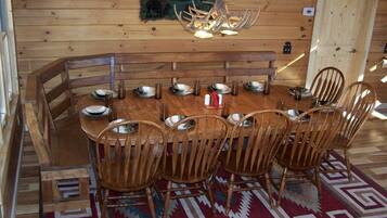 Ein Esszimmer mit Holzboden, einem großen Tisch und Stühlen, einer Chandelierleuchtre und einem an der Wand hängenden Gemälde.