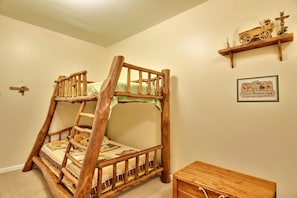 A bunk bed with a ladder, a small wooden chest, and a shelf with a toy car and figurines.