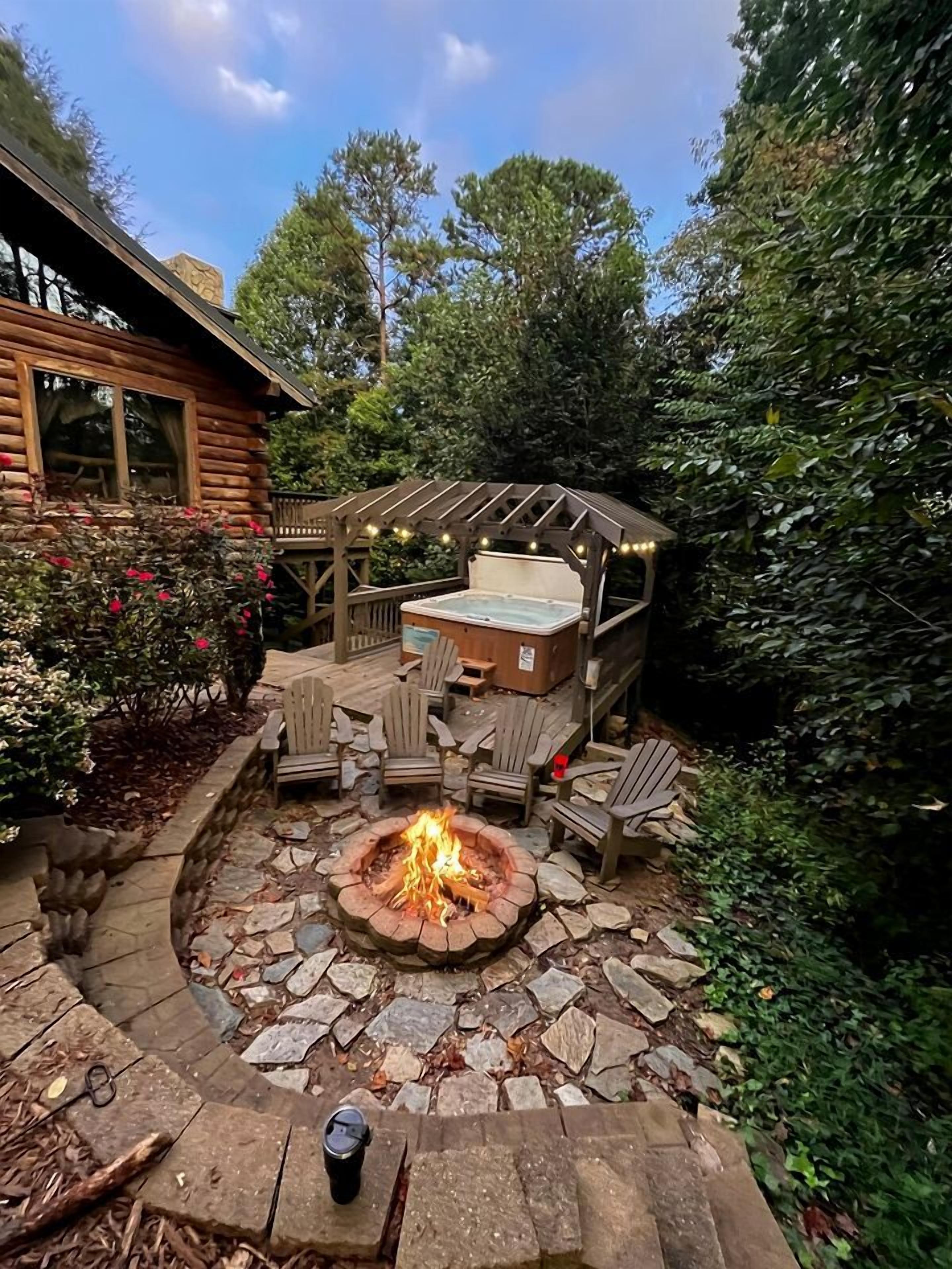 A wooden deck with a hot tub, fire pit, and Adirondack chairs.