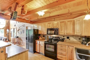 A wooden cabin interior with a kitchen featuring a refrigerator, stove, microwave, and wooden cabinets. - Luxury Vacation Rental with a Hot Tub for Rent in Clyde, North Carolina (Clyde)