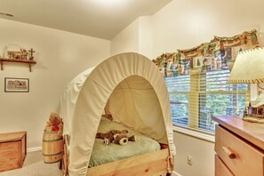 A child's bedroom with a canopy bed, a wooden dresser, a window with blinds, and a small shelf with a toy car and a framed picture. - Luxury Vacation Rental with a Hot Tub for Rent in Clyde, North Carolina (Clyde)
