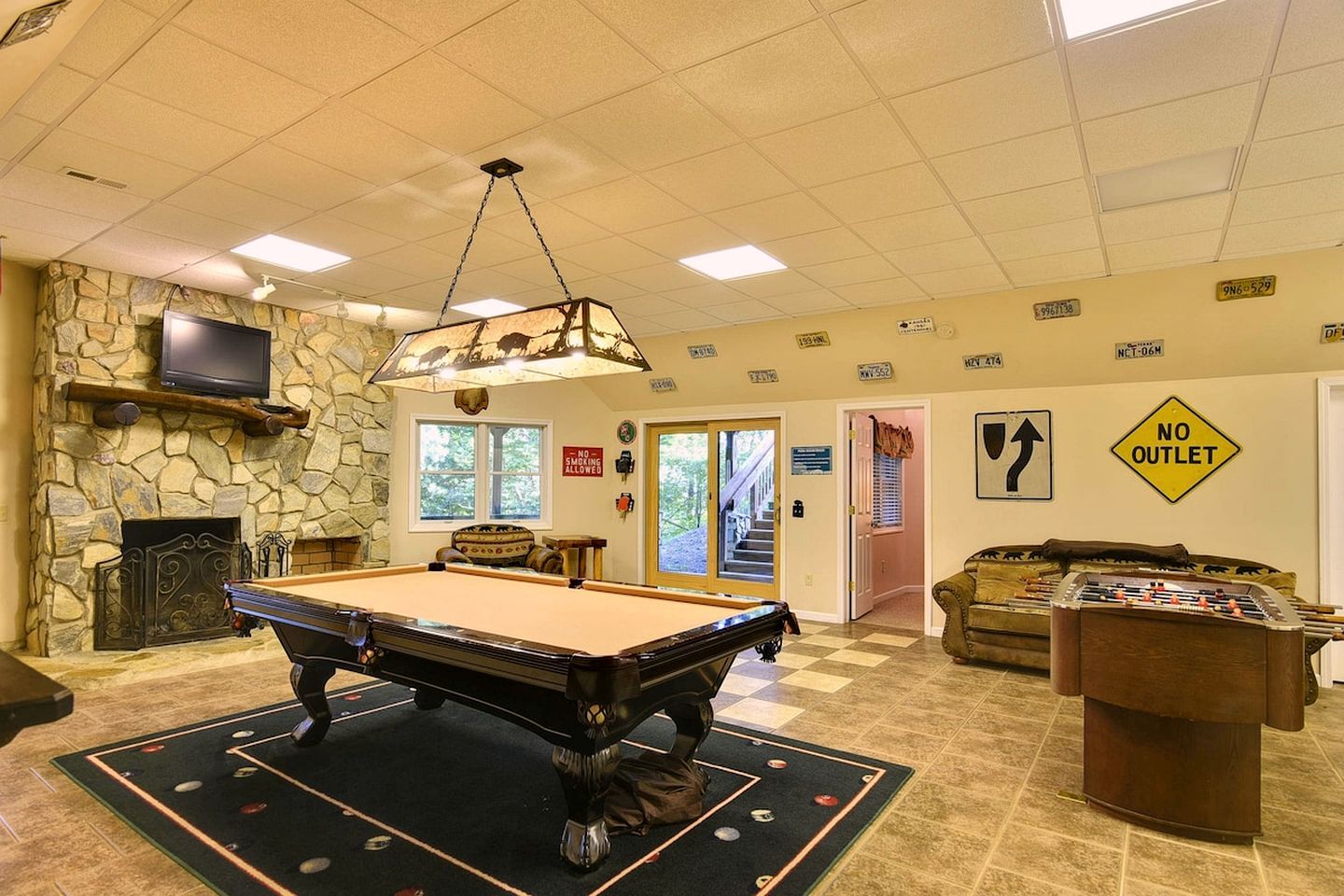A pool table in a room with a stone wall, a fireplace, and a sign indicating no outlet.