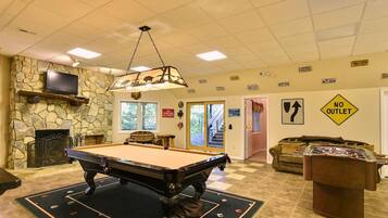A pool table in a room with a stone wall, a fireplace, and a sign indicating no outlet.