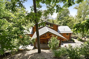A wooden cabin with a sloped roof, surrounded by lush greenery and trees. - Luxury Vacation Rental with a Hot Tub for Rent in Clyde, North Carolina (Clyde)