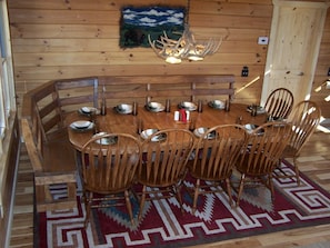A wooden dining room with a large table and chairs, a chandelier, and a painting on the wall. - Luxury Vacation Rental with a Hot Tub for Rent in Clyde, North Carolina (Clyde)