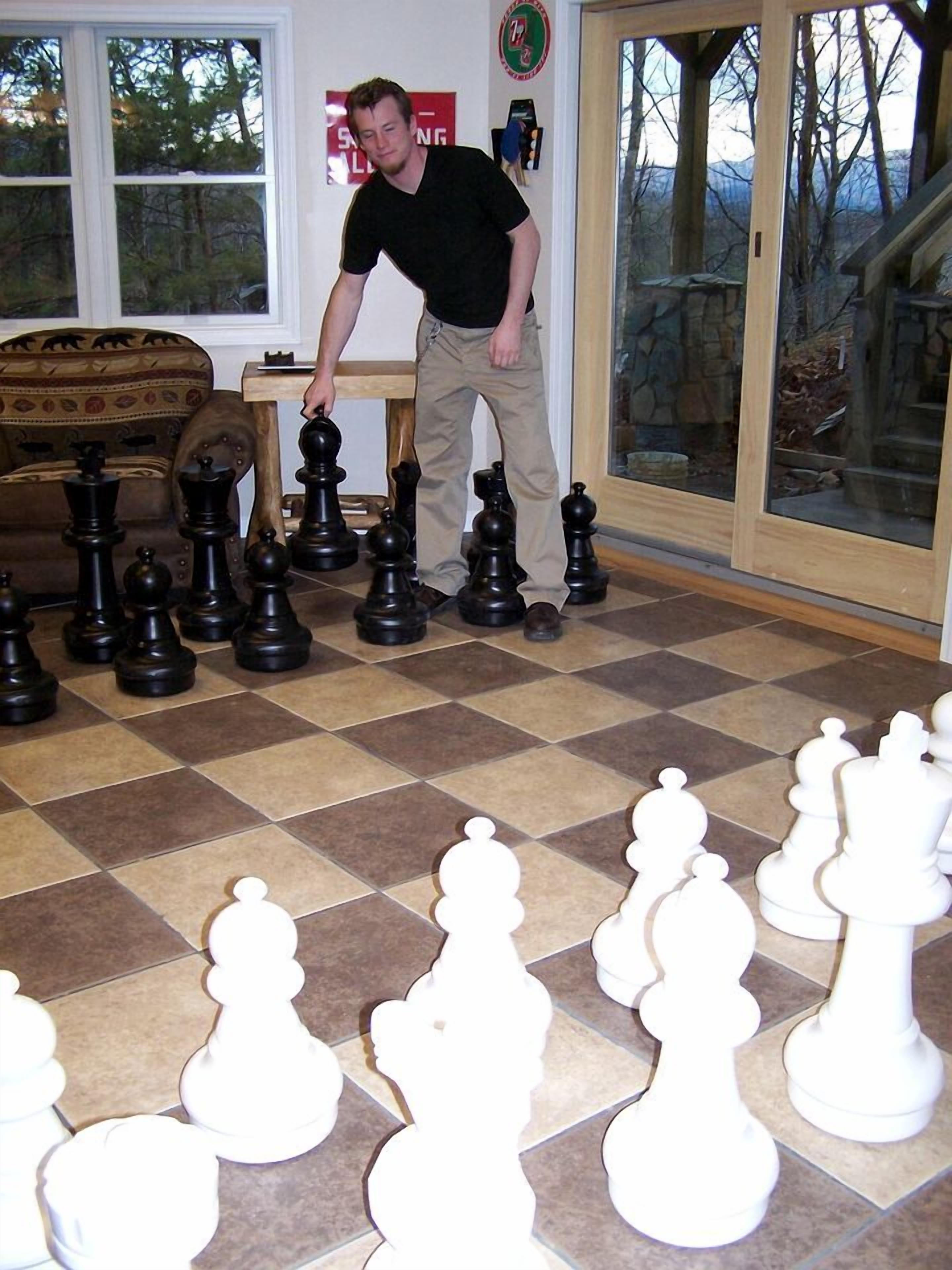 A man leaning over a chessboard with pieces arranged in two rows.