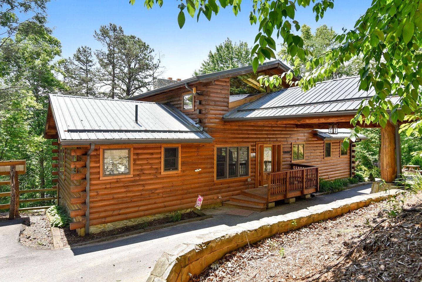 A log cabin with a porch, a covered deck, and a metal roof.