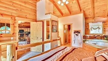 A wooden cabin interior with a bedroom, bathroom, and kitchen.