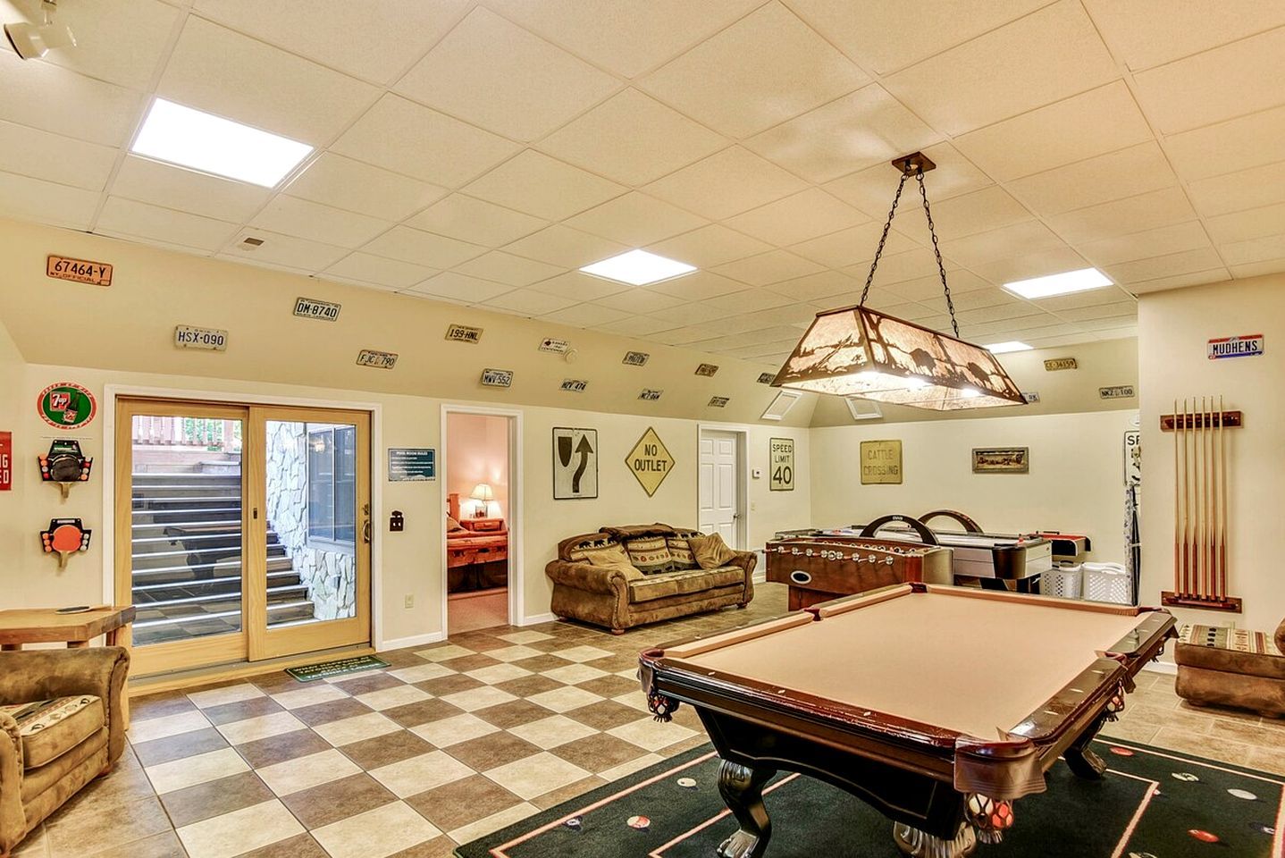 A spacious room with a pool table, a billiards rack, and a cozy seating area.