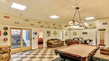 A spacious room with a pool table, a billiards rack, and a cozy seating area.