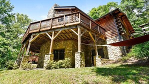 A cabin with a stone foundation, wooden balcony, and a sloped roof.