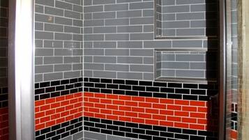 A corner of a room with a tiled wall featuring a brick pattern and a red and black horizontal stripe.