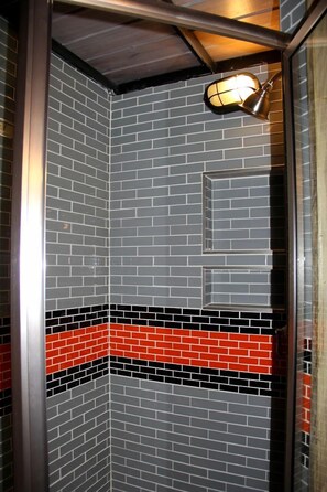 A corner of a room with a tiled wall featuring a brick pattern and a red and black horizontal stripe.