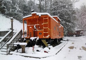 En stillastående vagn längst bak på ett tåg, placerad i en snöig miljö, med en trätrappa som leder upp till den.