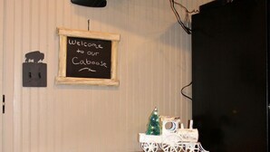 Een keuken met een houten tafel, twee krukken, een televisie boven de tafel en een kleine kerstboomversiering.