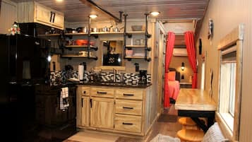 Una cucina compatta con mobili in legno, un frigorifero nero e un'area pranzo con una panca e un tavolo.