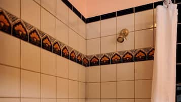 Un baño con paredes de azulejos blancos, cortina de ducha, bañera y barra de apoyo.