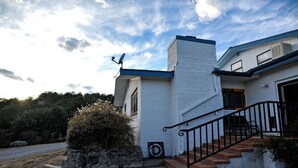 A modern house with a white exterior, a stone planter, and a black staircase leading to the entrance. - Spacious Cabin Rental with Beautiful Mountain Views near Pinos Altos, New Mexico (Silver City)