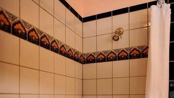 A bathroom with white tiled walls, a shower curtain, a bathtub, and a handrail.