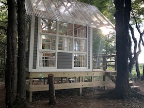 Una cabaña de madera con varias ventanas, una terraza y un techo de paja.