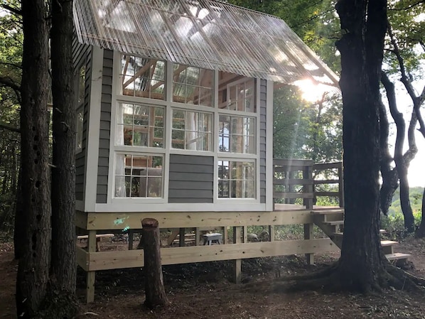 Una cabaña de madera con varias ventanas, una terraza y un techo de paja.