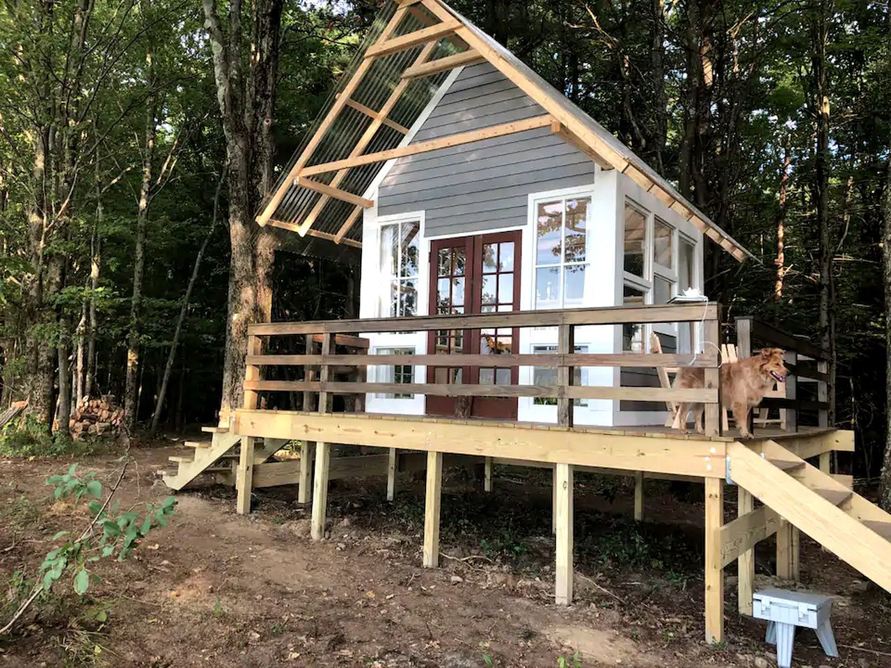 A wooden deck leading to a cabin with a pitched roof and large windows.