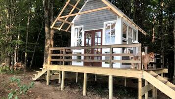 A wooden deck leading to a cabin with a pitched roof and large windows.