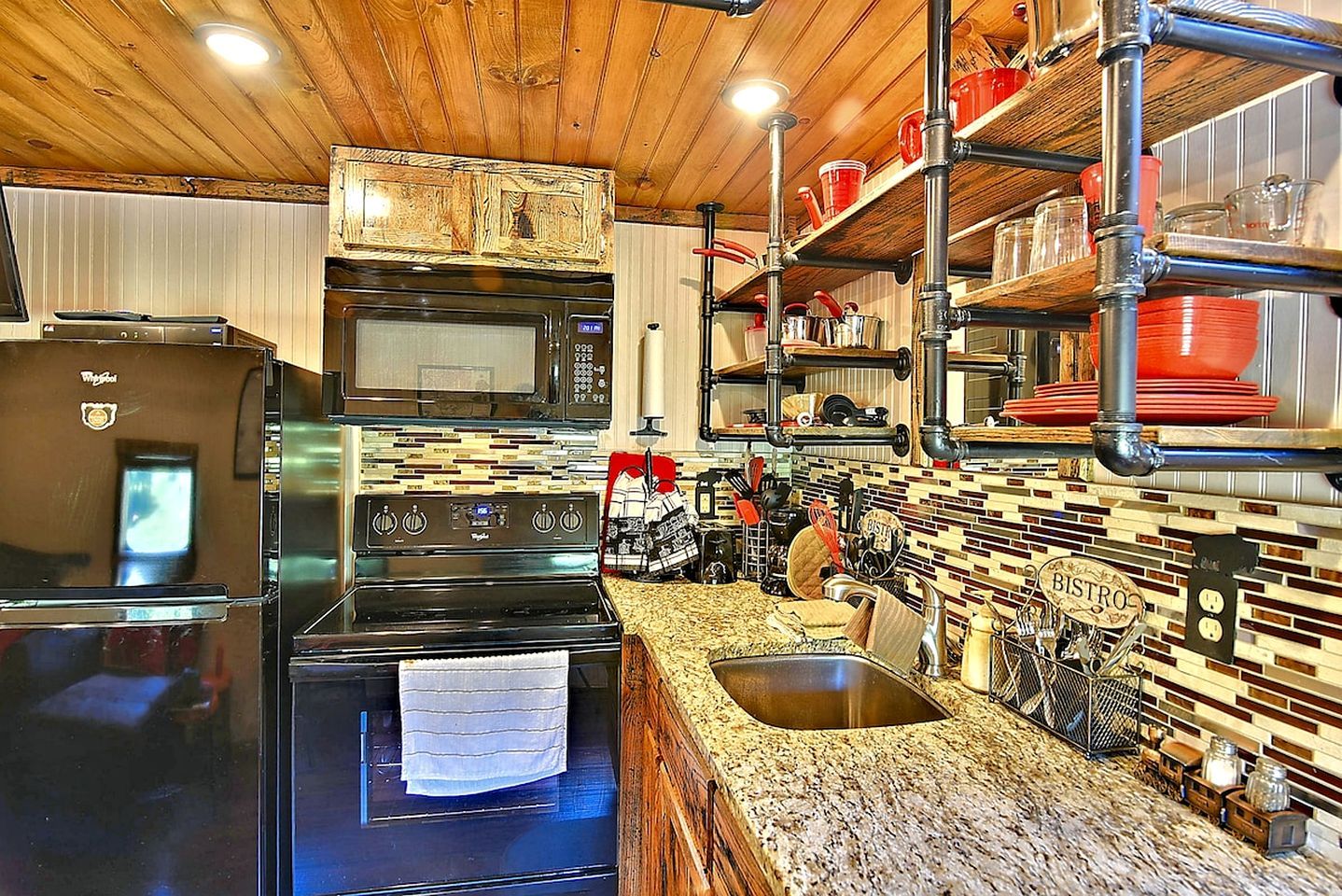 A kitchen with stainless steel appliances, a granite countertop, and a backsplash with a mosaic tile pattern.