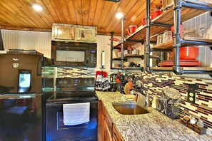 A kitchen with a refrigerator, stove, microwave, and a sink.