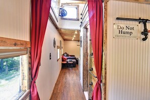 A narrow hallway with a red curtain, a sign reading 'Do Not Hump,' and a rustic wooden interior. - Glamping Caboose Rental Perfect for Families near Clyde, North Carolina (Clyde)