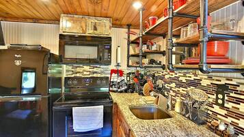 A kitchen with stainless steel appliances, a granite countertop, and a backsplash with a mosaic tile pattern.
