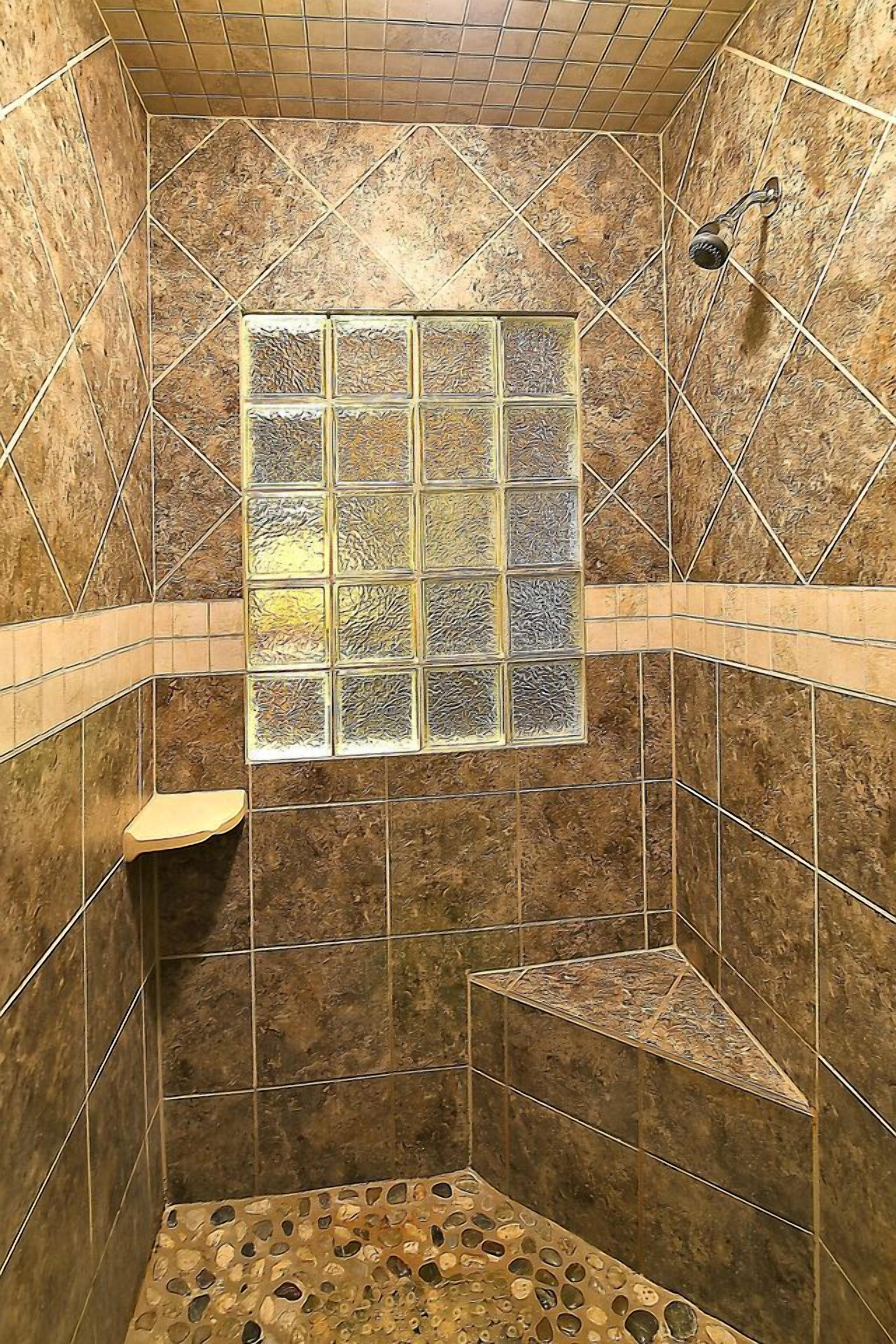 A shower with a tiled wall, a window, and a showerhead.