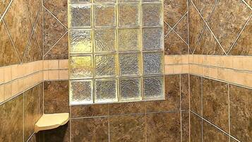 A shower with a tiled wall, a window, and a showerhead.
