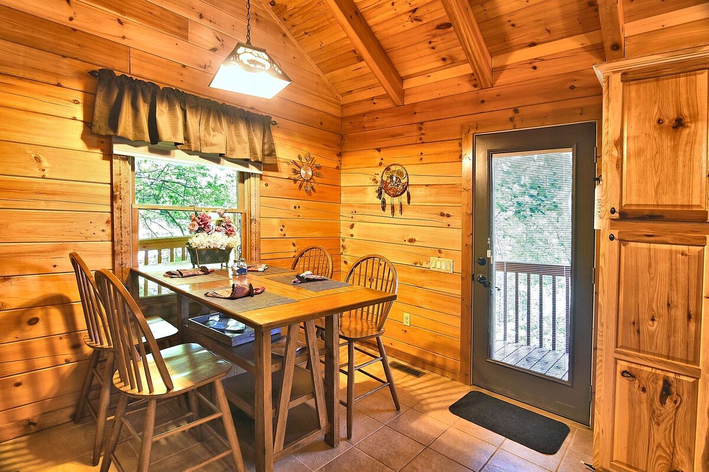 Un interior de madera con una mesa de comedor, sillas, un ventanal y una puerta.