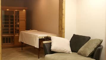 Une pièce comprenant une table de massage, un meuble en bois et un fauteuil rembourré.