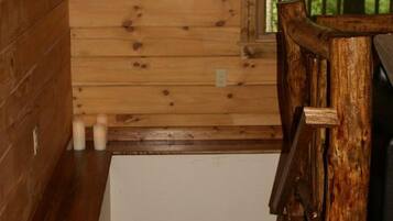 A wooden cabin interior with a staircase leading to a loft area.
