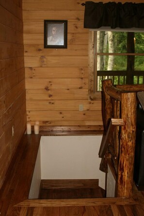 A wooden cabin interior with a staircase leading to a loft area.