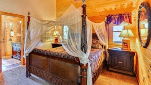 A four-poster bed with a canopy, wooden walls, a ceiling fan, and a large mirror.