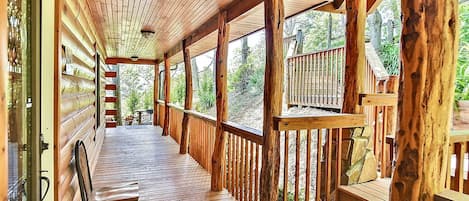 Eine Holzterrasse mit Geländer, einer Sitzbank und Blick auf den umliegenden Wald.