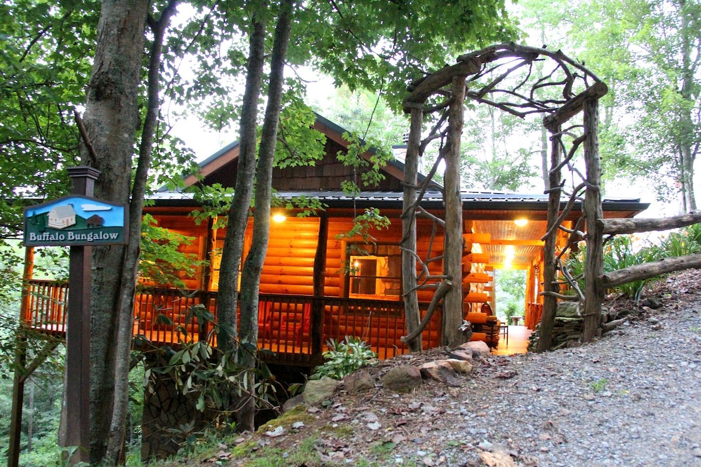 Une cabane en rondins avec un porche, entourée d’arbres, et une pancarte indiquant qu’il s’agit d’un « Buffalo Bungalow ».