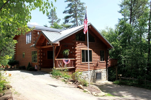 Eine Blockhütte mit Veranda, einer amerikanischen Flagge und einem Steinfundament.